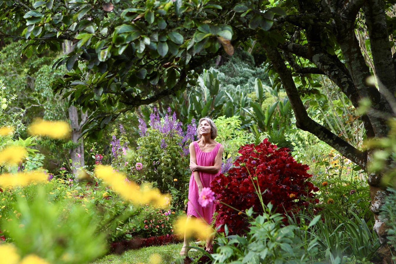 Corinna standing among purple salvia and deep red foliage, face lifted to the light